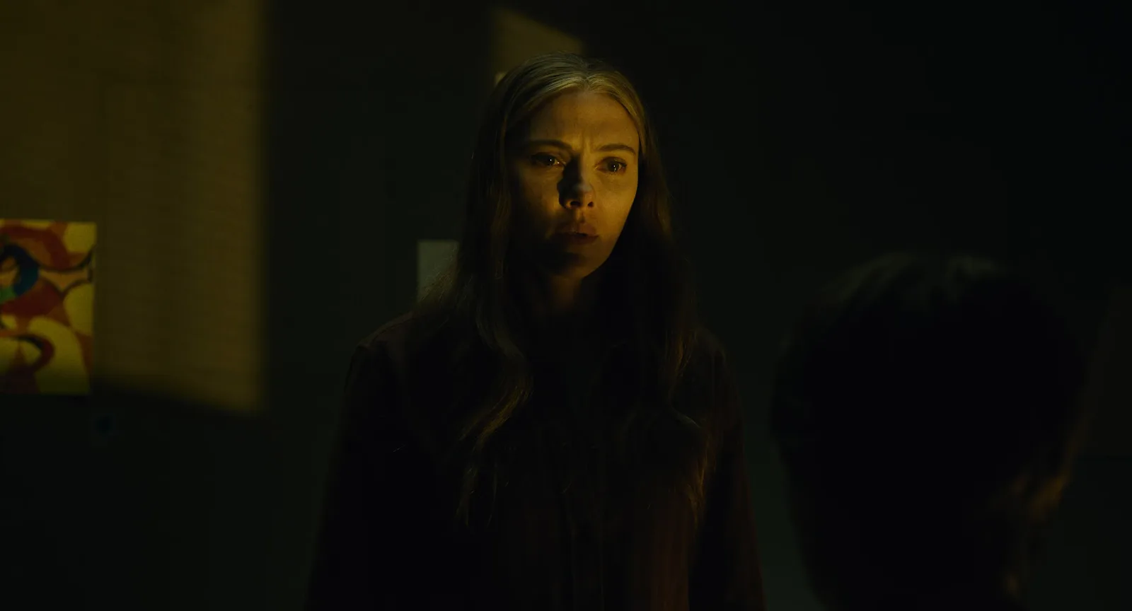Scarlett Johansson en Julie Miller, le visage à demi éclairé dans une pièce sombre, dans The Exorcist: Martyrs